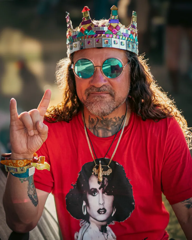 Character portrait of a festival-goer wearing a crown and mirrored glasses