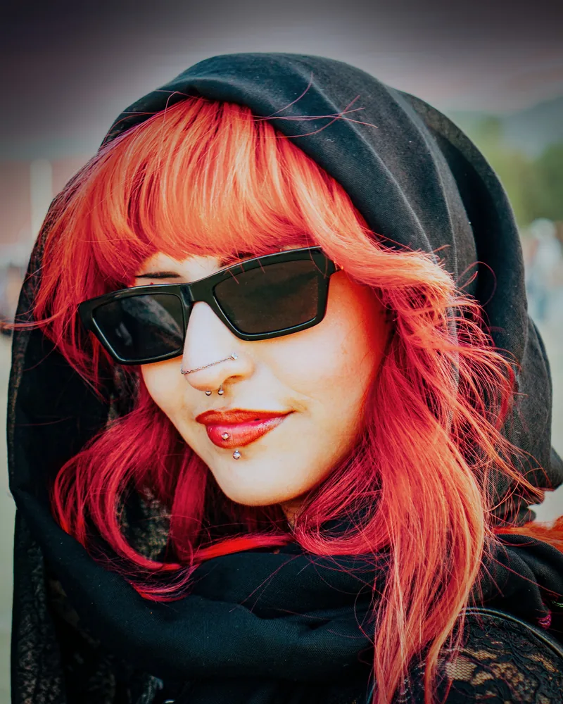 Street-style portrait with red hair, dark glasses and a hood
