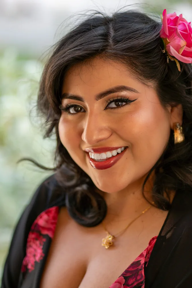 Warm close-up portrait of a smiling woman with a flower in her hair