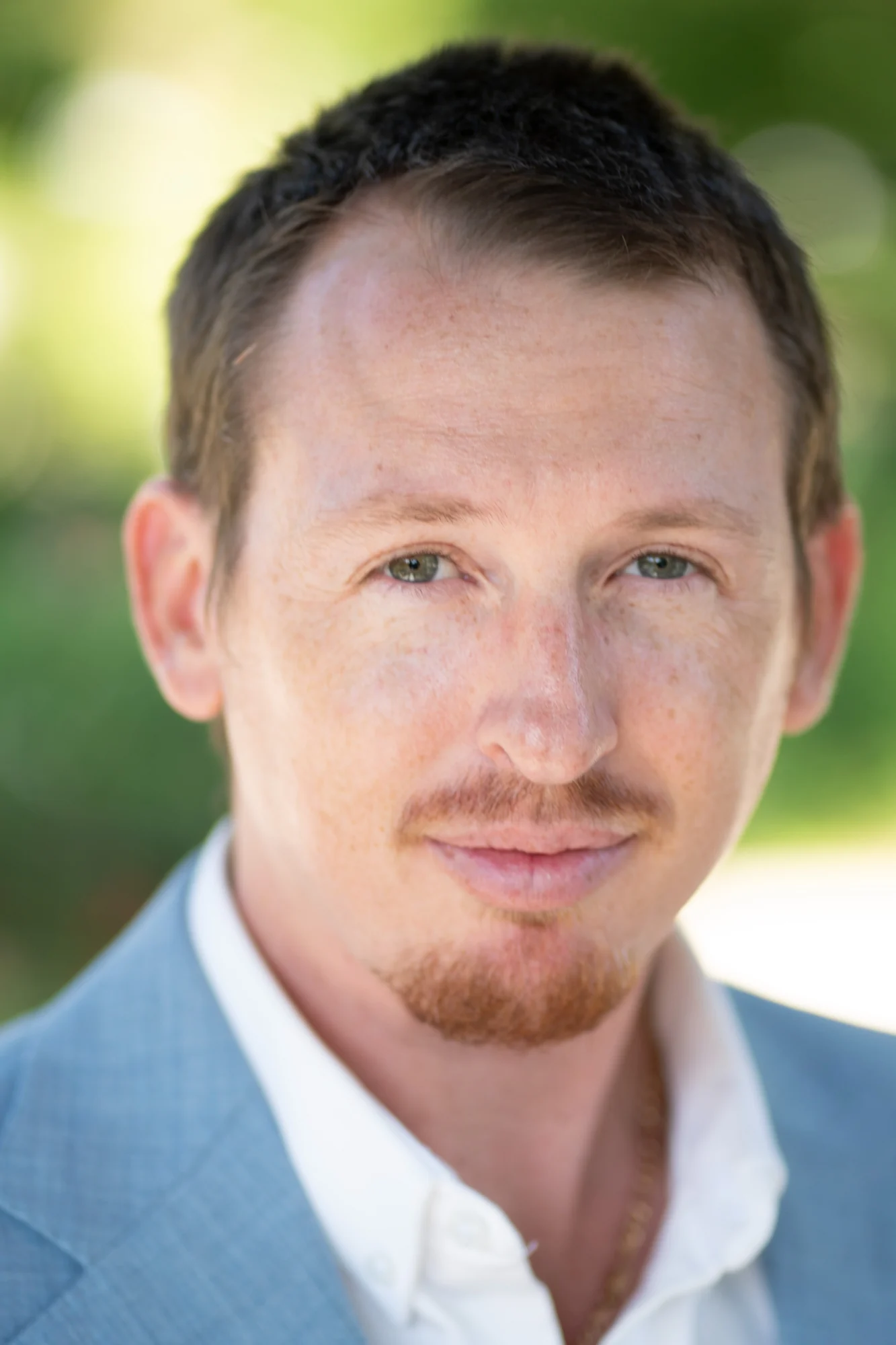 Natural-light headshot of a man in a pale blue jacket